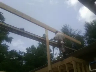 Carpenter setting a ridge beam over a new addition frame — Ice Dam Removal by Roofing Brothers in Bainbridge