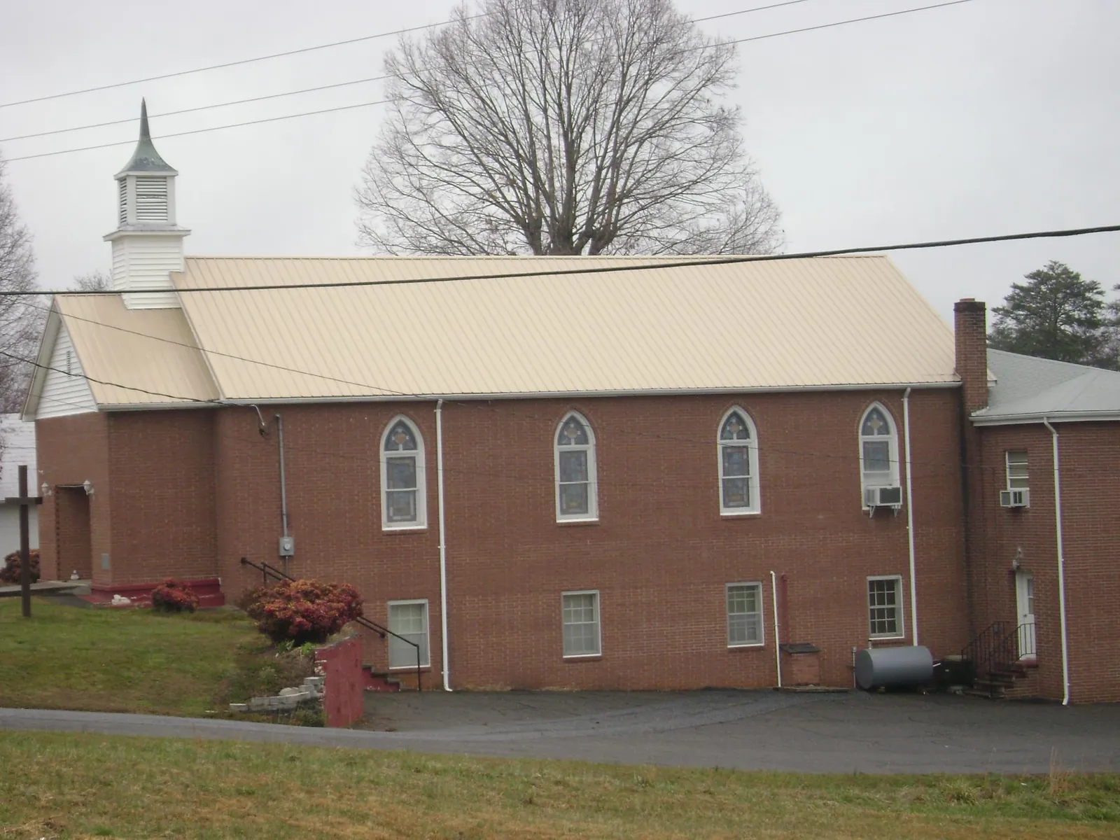 New tan metal roof on a brick church with a white steeple in Bainbridge